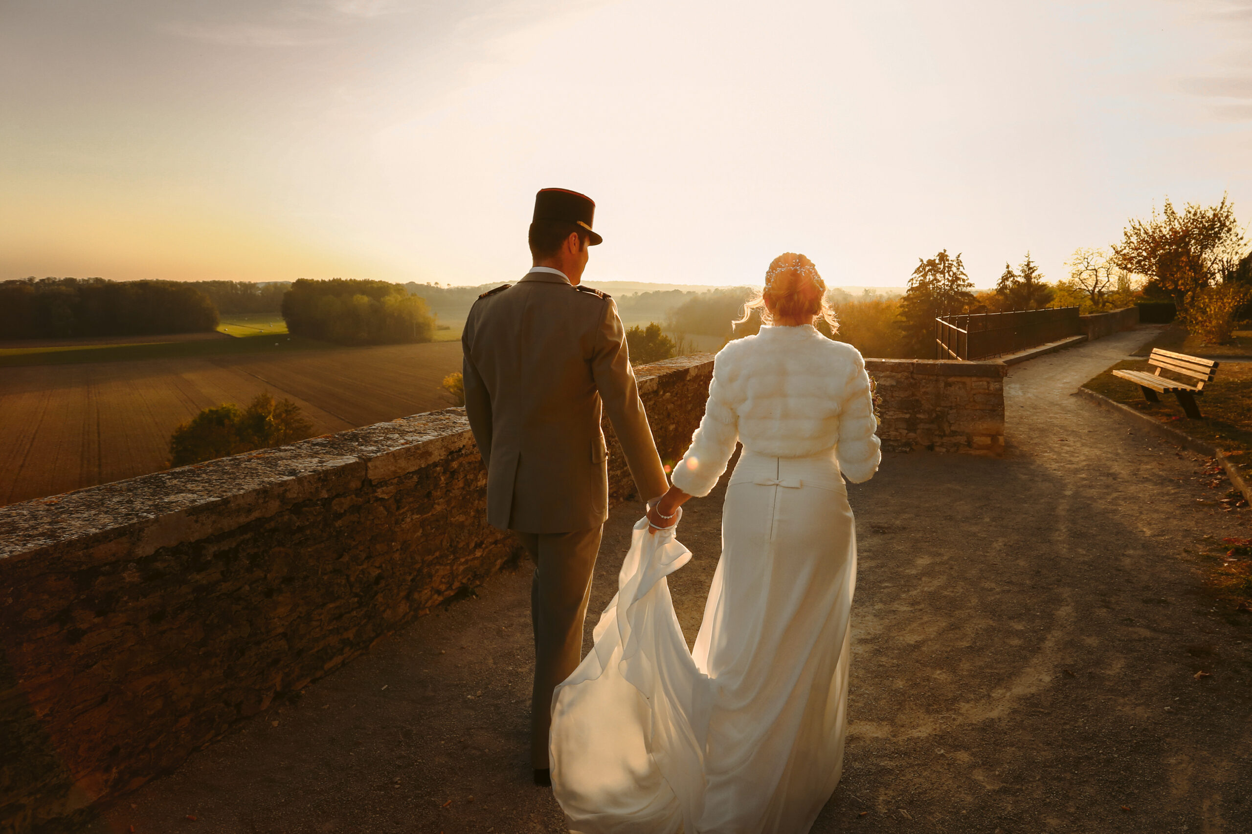 Photo d'un couple de mariés marchant vers le coucher de soleil